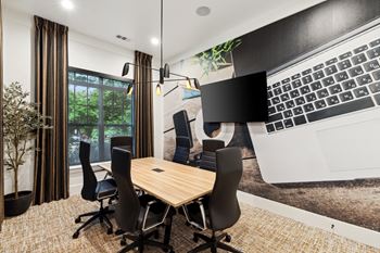 a conference room with a table and chairs and a large screen on the wall